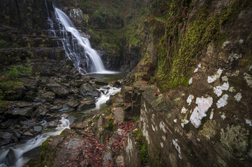 Coed y Brenin waterfall with long exposure surrounded by rocks in Wales, the UK
