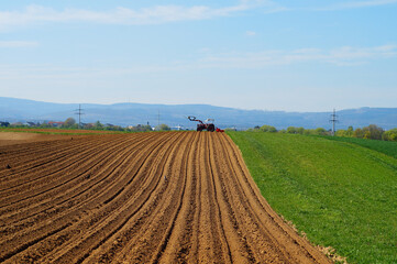 A tractor on the horizon of a freshly prepared potato field.