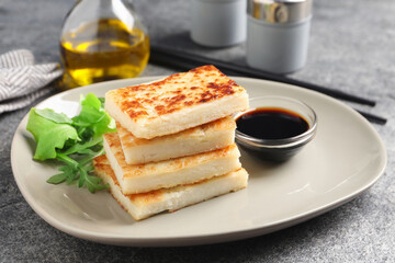 Delicious turnip cake with arugula and soy sauce served on grey table