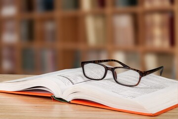 Old books, reading glasses on the wooden desk