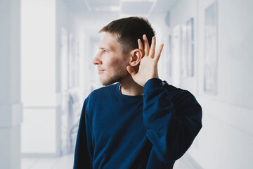 young male holding his hand over ear, hearing problems concept