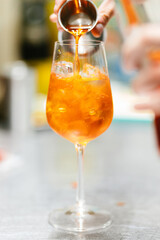 Vertical closeup of the hand preparing an Aperol Spritz drink.
