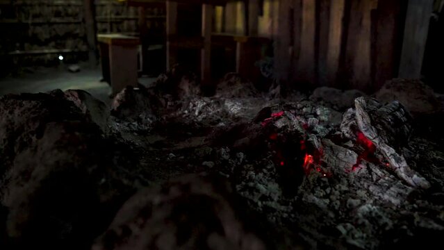 Handheld of wood burning and ashes In fireplace inside a Ruka, traditional Mapuche house in Chile