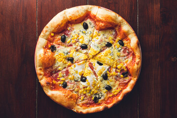 Closeup of the pizza with tomato base, cheese, pepperoni, ham, sweet corn, blue cheese, egg