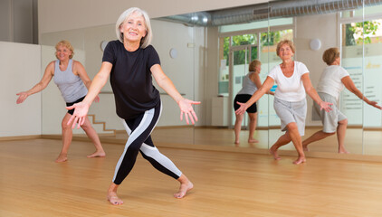 Aged women performing modern dance during their group training in fitness room.
