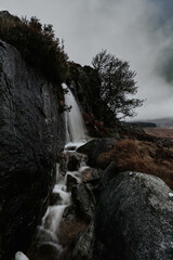 Vertical shot of the Wicklow Mountains and the waterfall on a cloudy day in Ireland