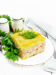 Casserole with potatoes and fish in plate on table