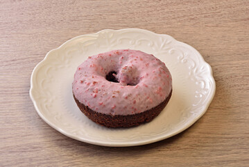 Cocoa cake donut with pink glaze on white plate