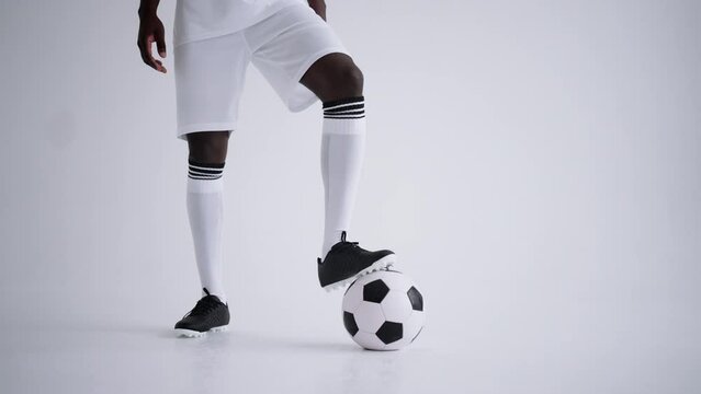 black football player is posing with ball in studio with white background, portrait of forward