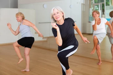 Fotobehang Group of three mature women performing modern dance in exercise room. © JackF