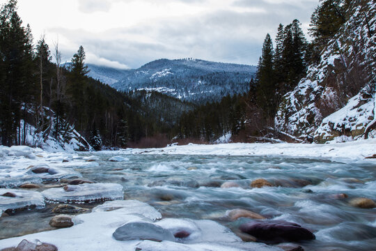 Serne view of a river flowing on tehh rocks in a freezing cold winter forest