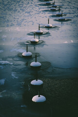 Vertical shot of snow-covered buoys in frozen water in daylight
