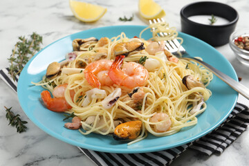Delicious pasta with sea food served on white marble table, closeup