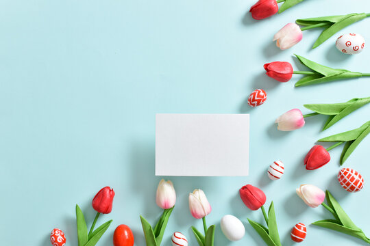 Background with tulips and Easter eggs with a blank sheet of paper.