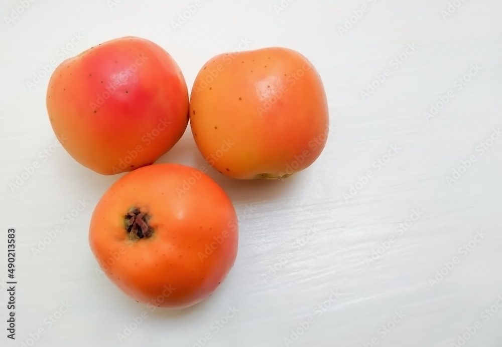 Sticker Closeup shot of fresh persimmon fruits on a white surface