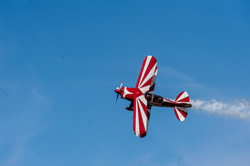 Red and white biplane flying against a blue sky - obrazy, fototapety, plakaty