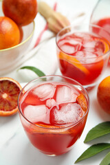 Tasty sicilian orange juice with ice cubes and fruits on white marble table