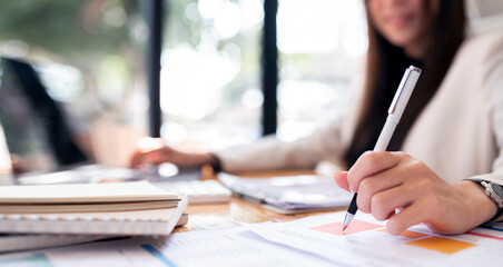 Businesswoman writing down notes on agenda, sitting at office desk, closeup view.