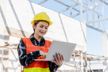 Fototapeta na wymiar Asian engineer architect worker woman holding laptop inspect and oversee infrastructure progress at construction site, engineering use computer to operate project and control worker to building