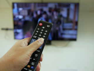 closeup of hand with the remote control television and presses the button.	
