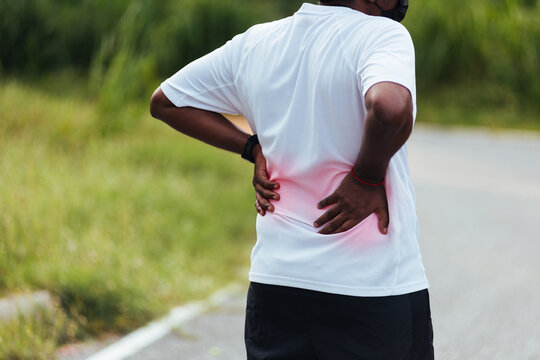 Close Up Asian Young Sport Runner Black Man Wear Watch Feel Pain On His Spine Low Back And Hip While Running At The Outdoor Street Health Park, Healthy Exercise Injury From Workout Concept