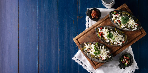 Mexican Tlacoyos. Mexican pre hispanic dish made of blue corn flour patty filled with refried beans. Popular street food in Mexico. Panoramic image with copy space. Top view