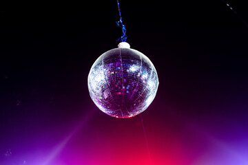 Hanging disco ball with laser lights falling on it
