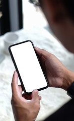 Young man holding mockup smart phone with white blank screen for graphic display montage.