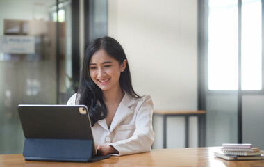 Pleasant young business woman checking financial data on computer tablet.