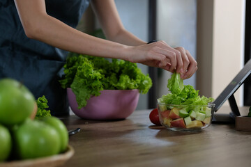 Young woman preparing vegetable salad in the kitchen. Healthy Lifestyle concept.