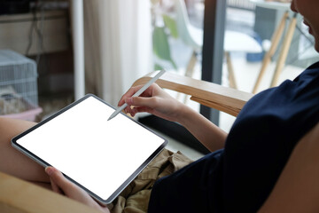 Casual young woman holding stylus pen writing on screen of digital tablet.