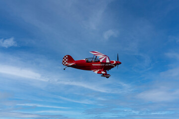 Fototapeta na wymiar Red and white biplane flying against a blue sky