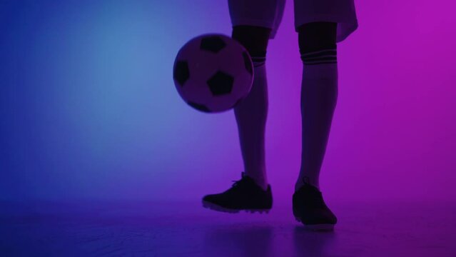 young african football player is doing keep-ups in studio, showing technical skills
