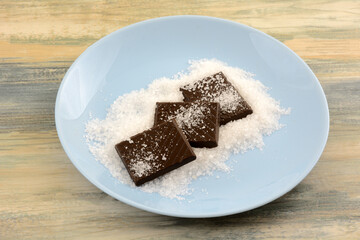 Dark chocolate candy bar square pieces with sea salt on blue snack plate