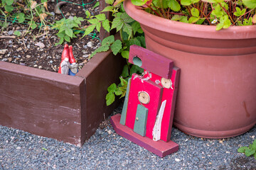 Two small red ceramic garden gnome figurines in a wooden vegetable box. There's a wooden red color...