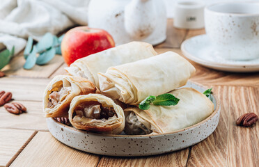 Mini apple strudel with pecans and mint on wooden table. Viennese pastry.