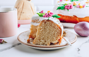 Fototapeta na wymiar Slice of Easter kulich cake on a plate over white marble table