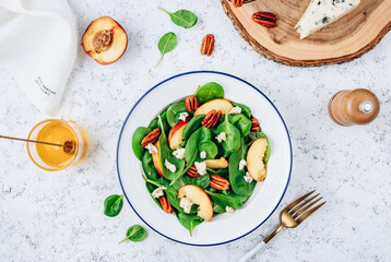 Healthy summer salad with spinach, peach, pecan nuts, blue cheese on white background