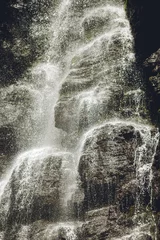 Fotobehang Cappuccino Bystre waterval stroomt over de rotsen