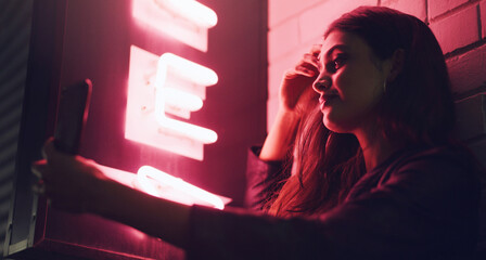 A night out is just what I needed. Shot of a young woman taking a selfie while standing outside a building at night.