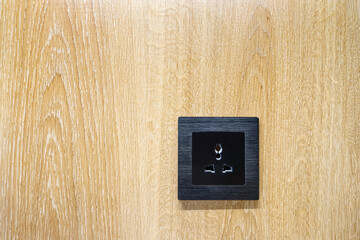 A black socket on a wooden textured wall