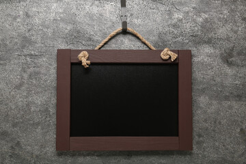 Clean small black chalkboard hanging on grey wall