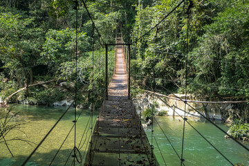 Hanging wooden bridge over Rio Claro Canyon in light and shadow, Doradal, Colombia