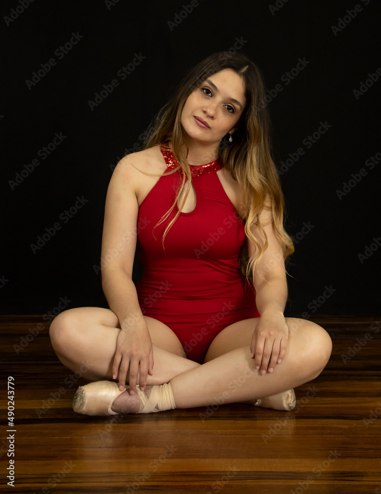 Wall mural Young latin woman ballet model. with ballet shoes. exercising happy, smiling. with black background and copy space for advertising. low key photo.