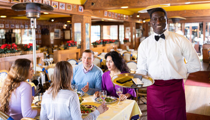 Fototapeta premium African American waiter brought mobile phones on the tray of the restaurant
