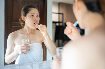 Asian woman brushing her teeth after waking up in the morning. Toothbrush is important tool for removing plaque and other soft debris from the teeth.
