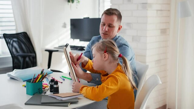 Father with his little daughter with Down syndrome learning at home.