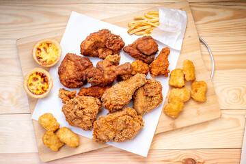 Fried chicken in woode plate on wooden background, Fried chicken set with nuggets, french fries and egg tart.