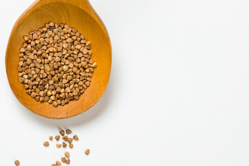 Buckwheat in a wooden spoon on a white background.