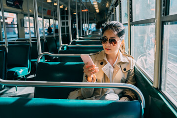 elegant businesswoman in sunglasses sending text message on mobile phone in bus. beautiful female...